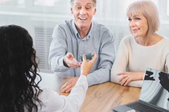 Female latin physician giving asthma inhaler to elderly couple