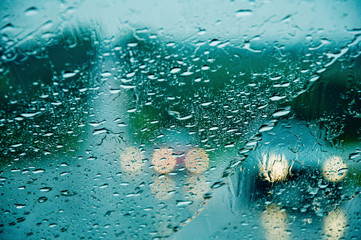 Heavy torrential rain thorugh the windscreen the windscreen. Cars with headlights are barely seen on the road. Selective focus