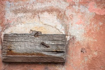 A piece of wood pinned to a stone board with a rusty nail