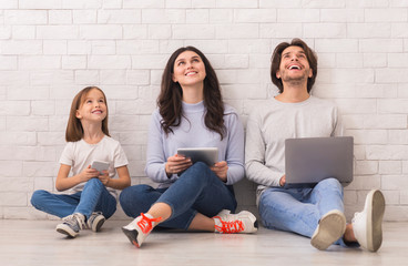 Family Sitting On Floor With Diverse Gadgets And Looking Upwards