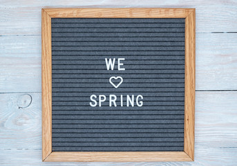 grey felt Board in a wooden frame with the text in English we love spring. heart sign instead of the word love. blank for design.