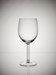 Splash of red wine in wine glass on white and gray gradient background. Isolated