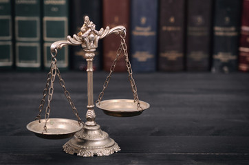  Scales of Justice on a black wooden background.