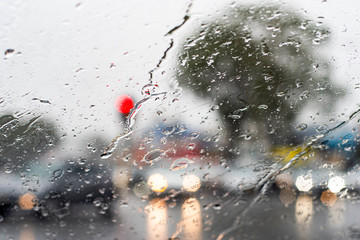 Heavy torrential rain through the windscreen. Cars with headlights are barely seen on the road. Selective focus