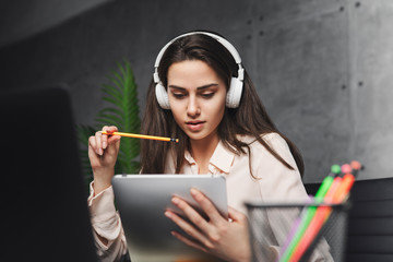 Womanl in headphones learning foreign language online. Young female listening to music and working on project. Wireless connection and great sound quality in earphones. Student getting education