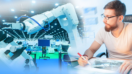 Testing an industrial robot. The engineer monitors the operation of the programmable robot and...