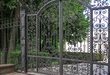 Beautiful forged cast iron grille. The stylish landscape is surrounded by summer greenery....