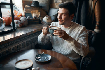 awesome man sitting in caffe and drinking hot tea in front of window, close up side view photo, good morning, good day with tasty coffee