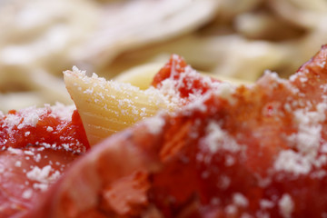 Cooked Penne macaroni with tomato sauce, parmesan and prosciutto