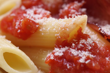 Cooked Penne macaroni with tomato sauce, parmesan and prosciutto