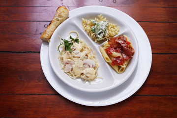 A white plate with three types of cooked  pasta
