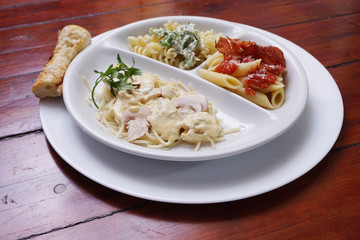 A white plate with three types of cooked  pasta