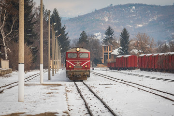 Velingrad railway station, Bulgaria - February 8, 2020: Train with red locomotive and green wagons arrives at the train station.