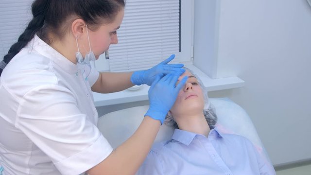 Cosmetologist applying moisturising healing cream after injections biorevitalization on woman face skin on papulas in cosmetology. Beautician ending mesotherapy lifting procedure in beauty clinic.