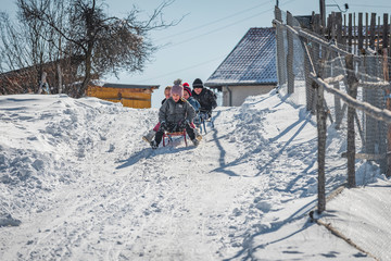 Fototapeta na wymiar Grashevo village, Rhodope mountains, Bulgaria - 02.08.2020: Little children having fun riding ice slide in winter