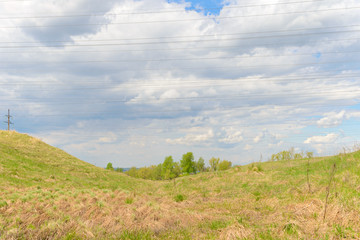 Landscape with grass in a ravine and power lines against the sky