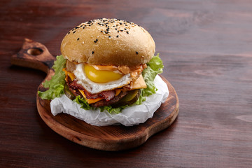 Appetizing burger on the board on a dark wooden table