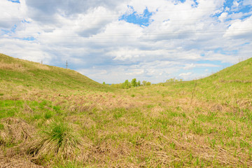 Landscape with grass in a ravine and power lines against the sky