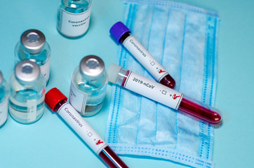 Test tube with positive Coronavirus test blood sample and vaccine bottle in the medical laboratory.