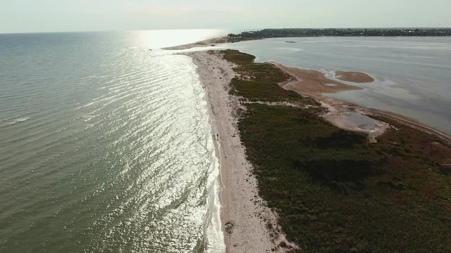 Aerial shot of a straight sandspit touching a curvy line at sunset in summer  
