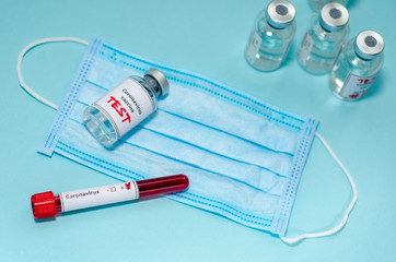 Test tube with positive Coronavirus test blood sample and vaccine bottle in the medical laboratory.