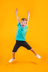 Fototapeta na wymiar Portrait of jumping funny boy on color background