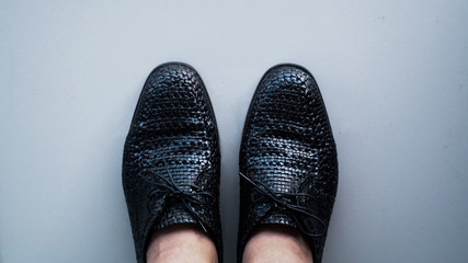 Black leather shoes with a knit pattern.