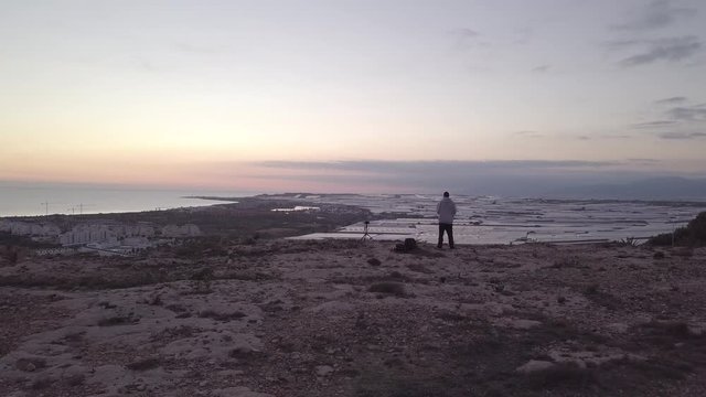 Aerial View Of Man With A Camera On Top Of A Cliff looking the sunset
