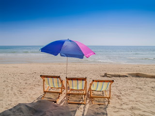 view of beach umbrella and three beach chairs on white sand beach with blue-green sea and blue sky background, Klong Khong Beach, Ko Lanta island, Krabi, southern of Thailand.