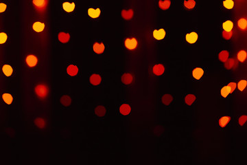 Abstract blur defocused background black, red-orange-yellow lights highlights, bokeh hearts, soft focus