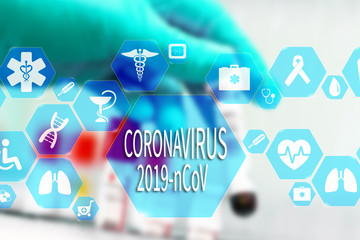 Coronavirus 2019-nCoV words on the virtual screen and Doctor with a vial of blood for the background.  Coronavirus outbreak awareness.
