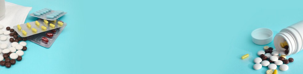Different blisters and spilled tablets, pills on mint background. Medicine health care or addiction concept. Banner.