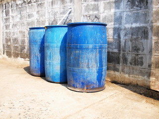 A group of blue trash wall. Old dirty plastic bucket and three roadside trash for support from the community in the city. On the background wall brick block with space reproduction. Selective focus.