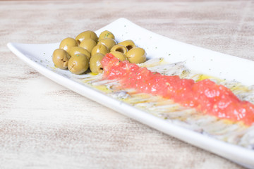 Plate of olives with sardine and tomato in their vinegar sauce