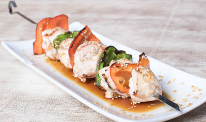 Meat skewer with red and green peppers hung vertically