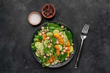 plate of pumpkin salad, avocado, cucumber, chickpeas, lettuce on a stone background.