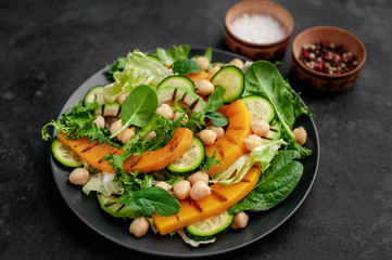 plate of pumpkin salad, avocado, cucumber, chickpeas, lettuce on a stone background.