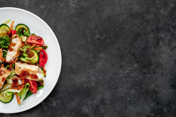 plate of tomato, chicken, cucumber, carrot, soy sauce salad in a plate on a stone background with copy space for your text