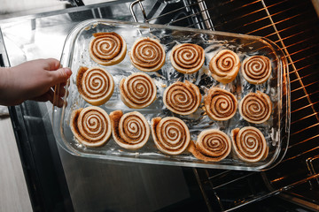 The girl makes homemade cinnamon rolls, cut into dough buns. The view from the top, hands on the picture