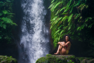 outdoors tropical lifestyle portrait of young attractive and happy hipster girl enjoying nature excited feeling free at amazing beautiful waterfall in exotic holidays travel