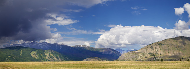 Mountain valley. Thundercloud over the mountain peaks, panoramic image.