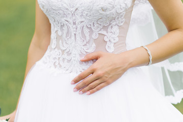 Obraz na płótnie Canvas Hand of the bride lying on the wedding white dress, wedding manicure