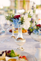 Beautiful silver vase with a bouquet of flowers in the decor of the wedding table and wedding, birthday, home