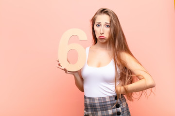 yound blonde woman sad, depressed, unhappy, holding a number 6.