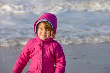 Portrait of a pretty little girl walking on the beach with her little dog