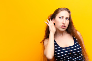 yound blonde woman looking serious and curious, listening, trying to hear a secret conversation or...