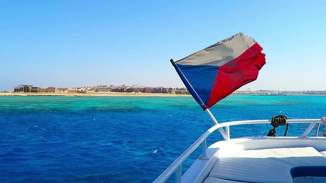 Czech flag on the boat. Adventure tourist vacation ship in the blue sea with flag. Flag on the ship, blue sea background, empty desert coastline.