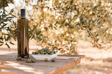 green olives and oil on table in olive grove