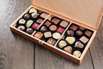 Different chocolate candies in wooden box.