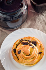 French bread with a Cup of black coffee on a linen tablecloth. French bread with coffee for Breakfast. Wholesome breakfast. Morning meal. Baking with raisins. Sweet bun.